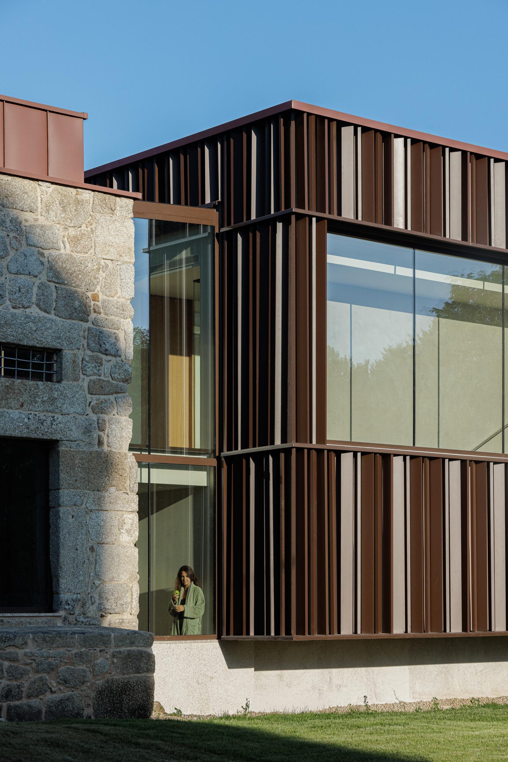 Detalhe da fachada do novo volume em lamelas metálicas e vidro, com a estrutura em pedra ao lado — MS COLLECTION AROUCA arquitectura MIMOOL ARQUITECTURA & INTERIORES fotografia Ivo Tavares