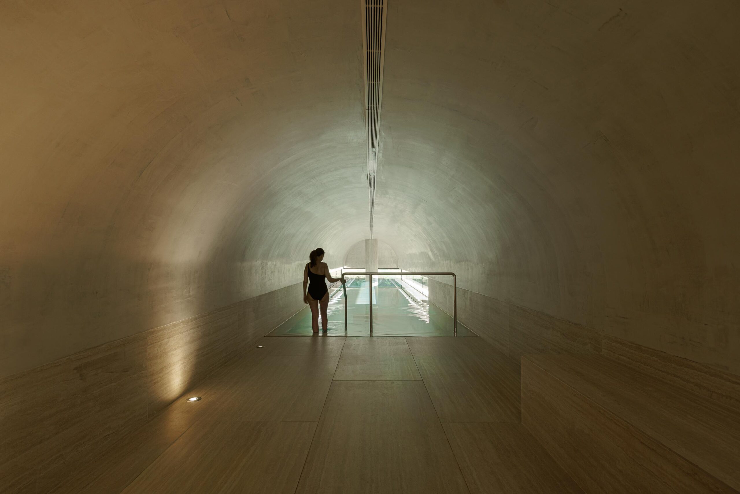Piscina interior com teto abobadado, pavimento em pedra clara e iluminação zenital, com vista para o exterior — MS COLLECTION AROUCA arquitectura MIMOOL ARQUITECTURA & INTERIORES fotografia Ivo Tavares