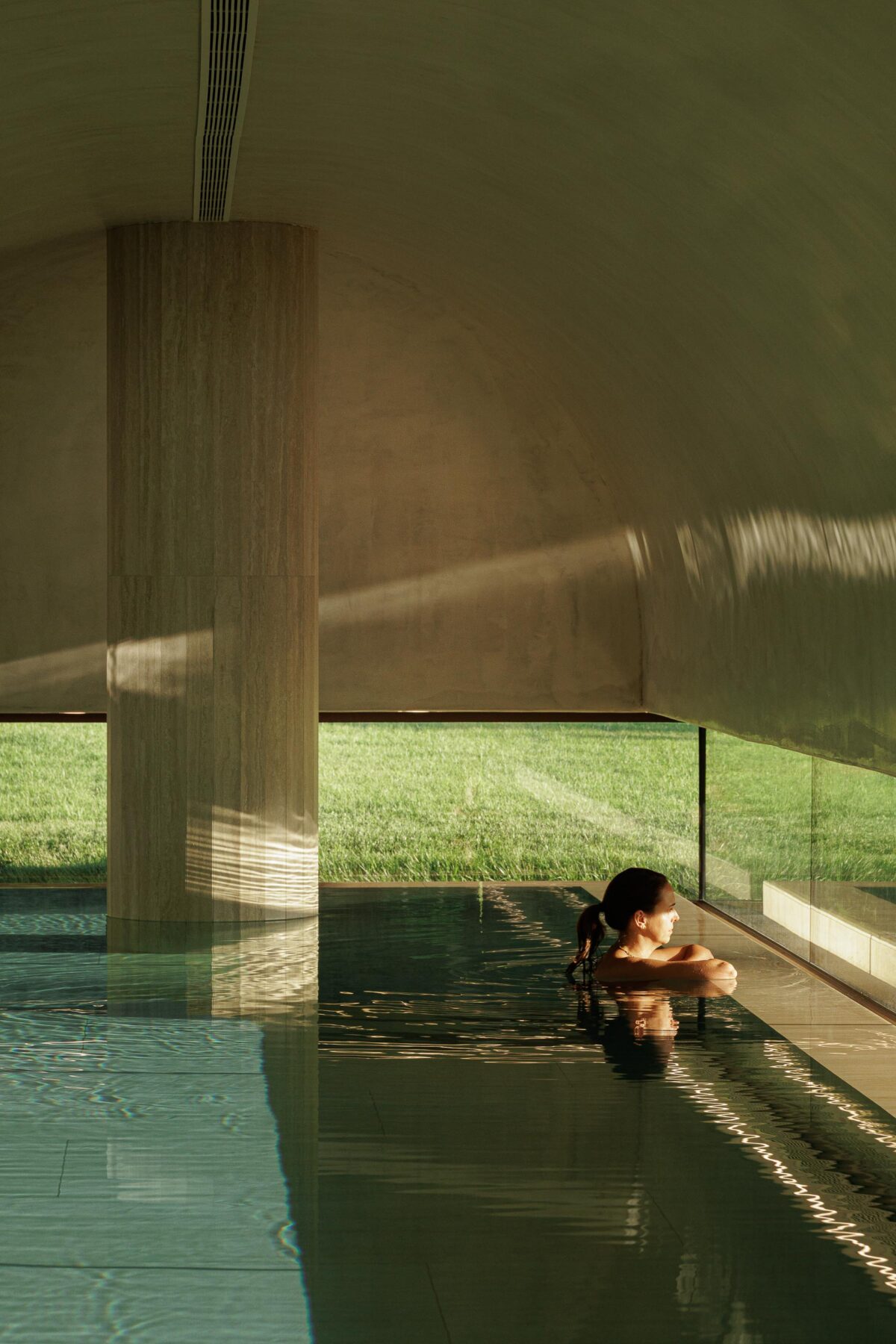 Detalhe da piscina interior com coluna em pedra, teto abobadado e vista para o exterior — MS COLLECTION AROUCA arquitectura MIMOOL ARQUITECTURA & INTERIORES fotografia Ivo Tavares