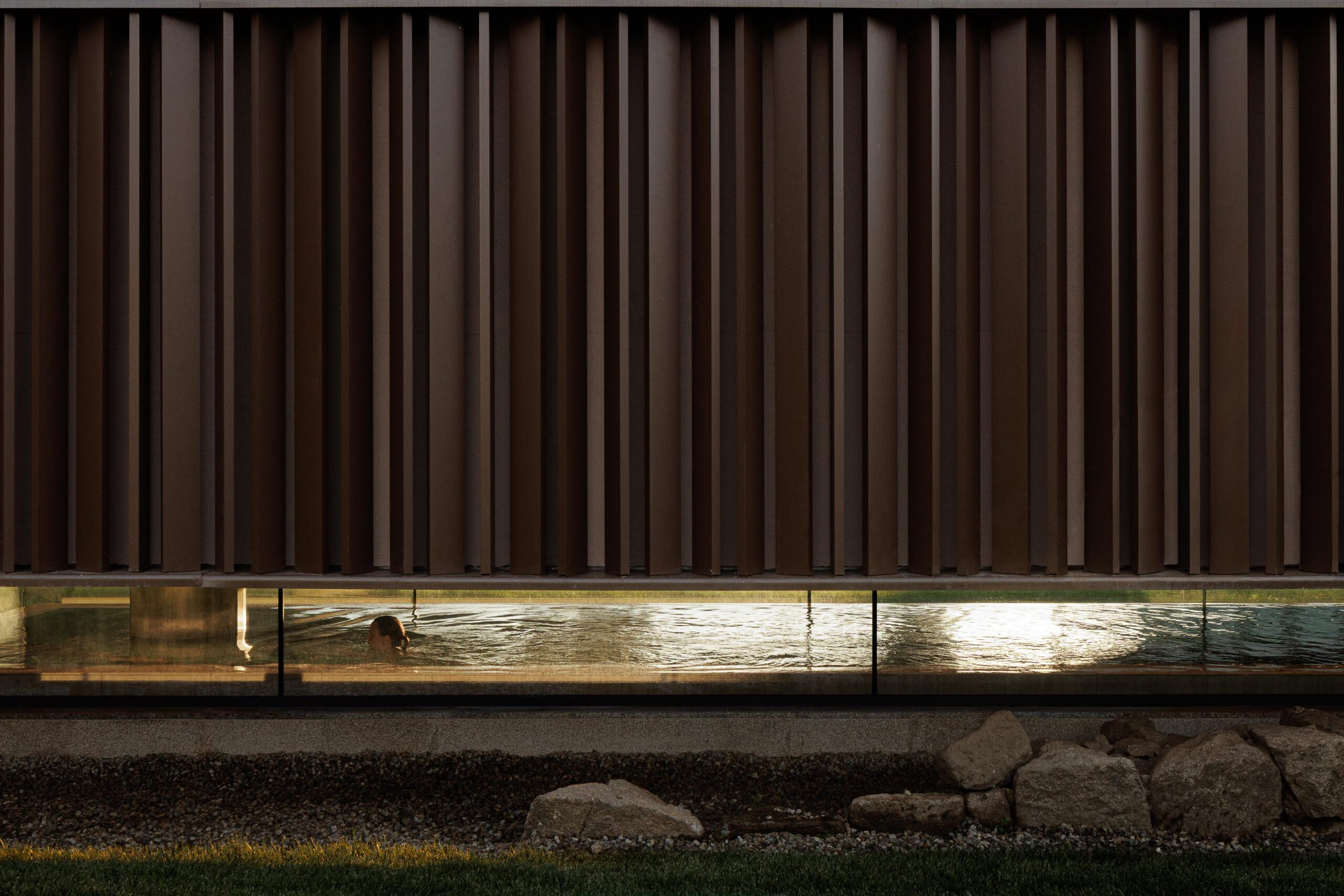 Detalhe da fachada em lamelas metálicas, com a piscina interior visível através de um vão envidraçado — MS COLLECTION AROUCA arquitectura MIMOOL ARQUITECTURA & INTERIORES fotografia Ivo Tavares