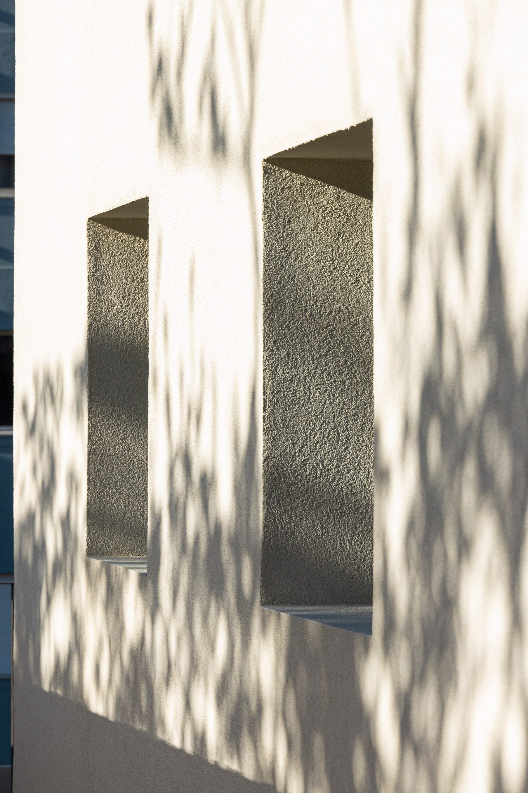 Detalhe dos vãos verticais na fachada branca, com profundidade e textura rugosa — Casa sem Rua