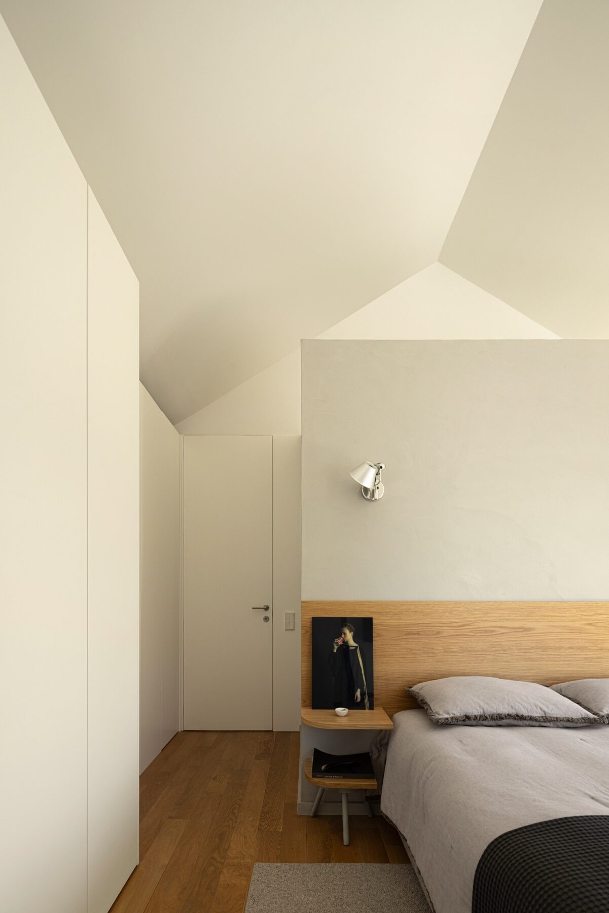 Quarto com pavimento em madeira de carvalho, cabeceira em madeira e armários brancos — Casa sem Rua