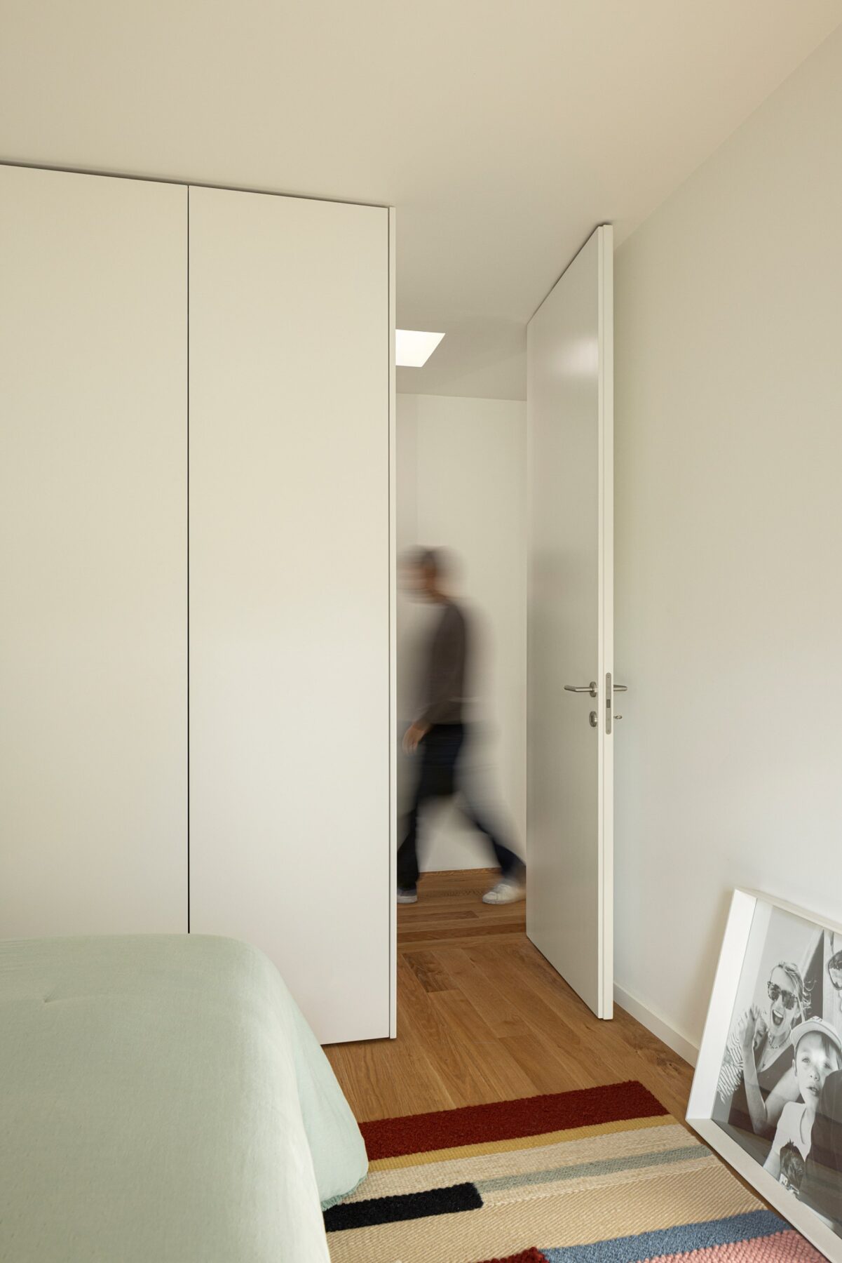 Quarto com pavimento em madeira de carvalho, armários brancos e porta aberta para o corredor — Casa sem Rua