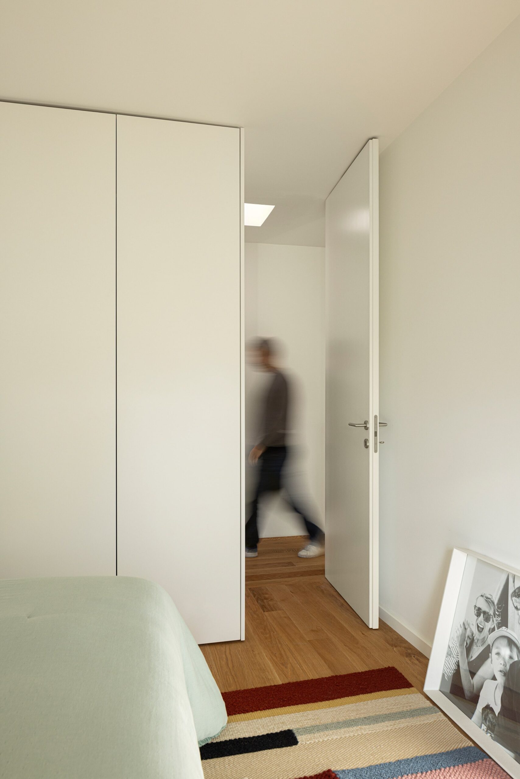 Quarto com pavimento em madeira de carvalho, armários brancos e porta aberta para o corredor — Casa sem Rua