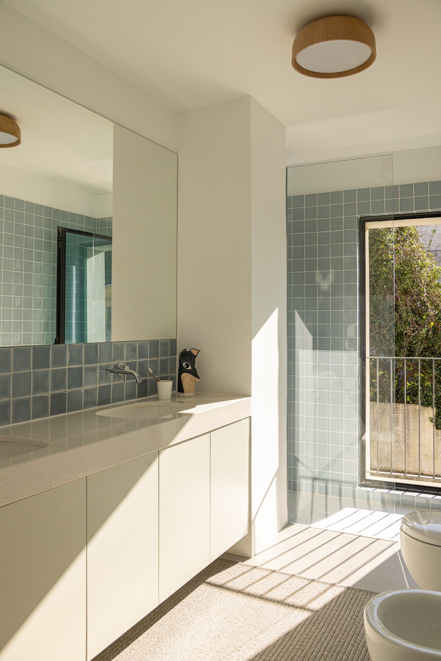 Casa de banho com azulejos azuis, lavatório duplo e vão com varanda — Casa sem Rua
