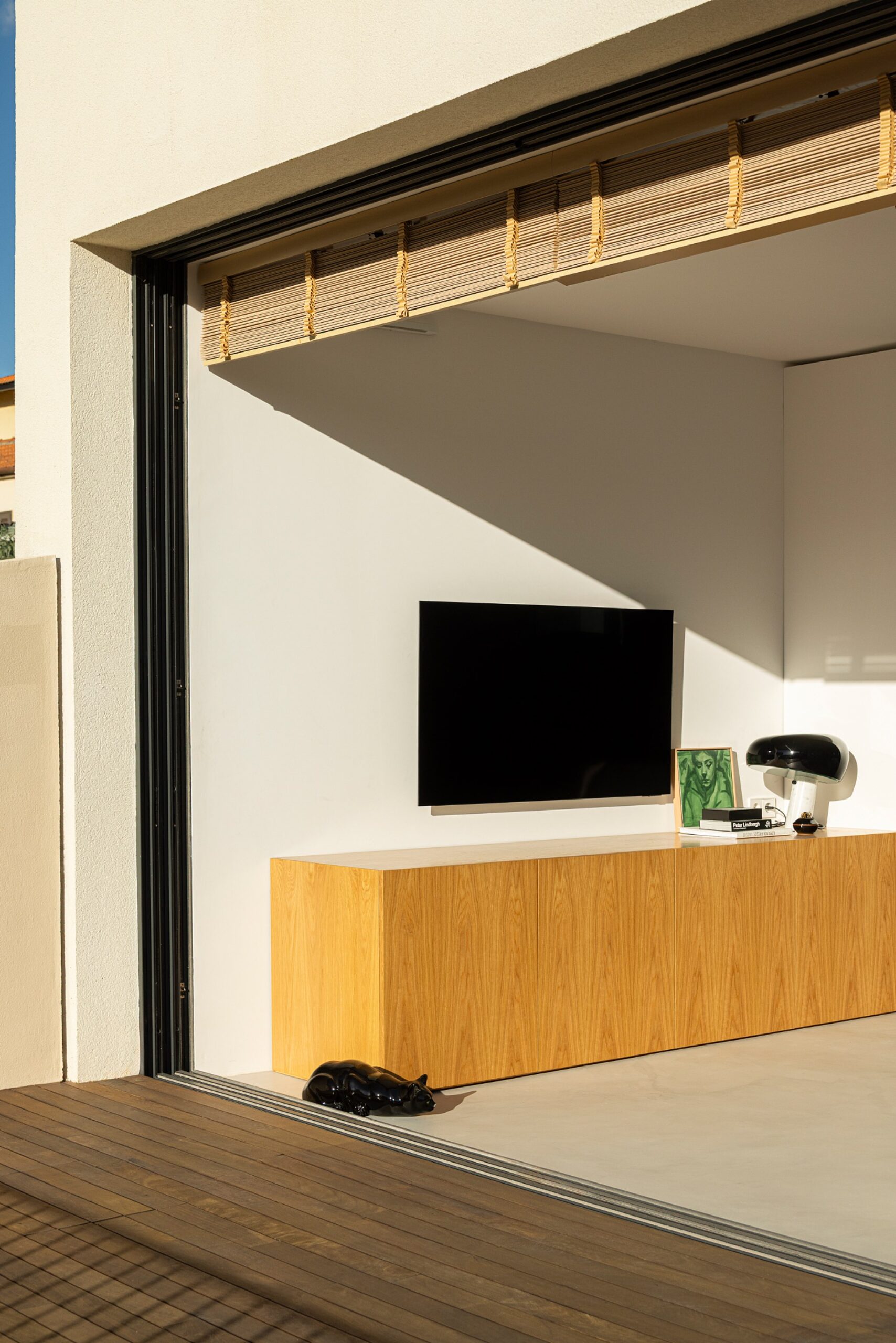 Sala de estar com pavimento cinzento, móvel em madeira clara e vão de correr para o exterior — Casa sem Rua