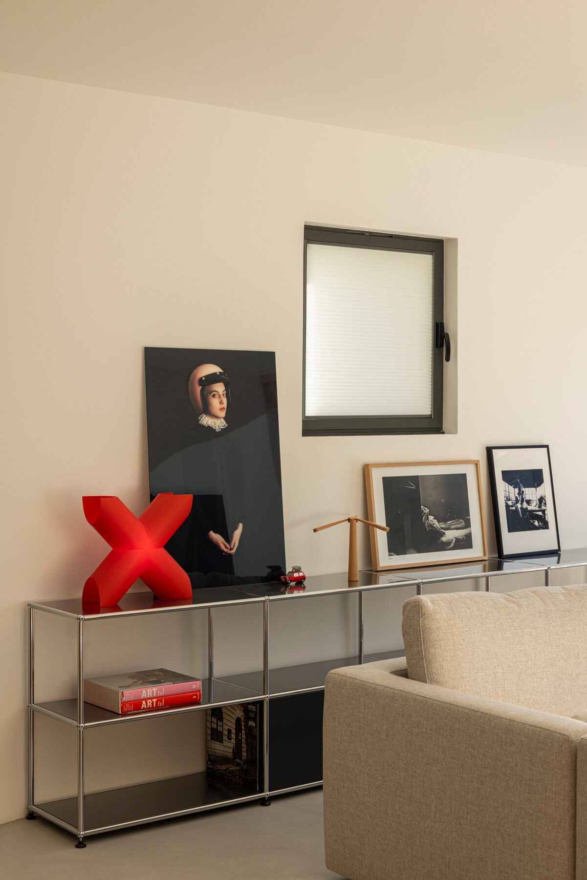 Detalhe de estante metálica com objetos decorativos e quadro, ao lado de um sofá — Casa sem Rua