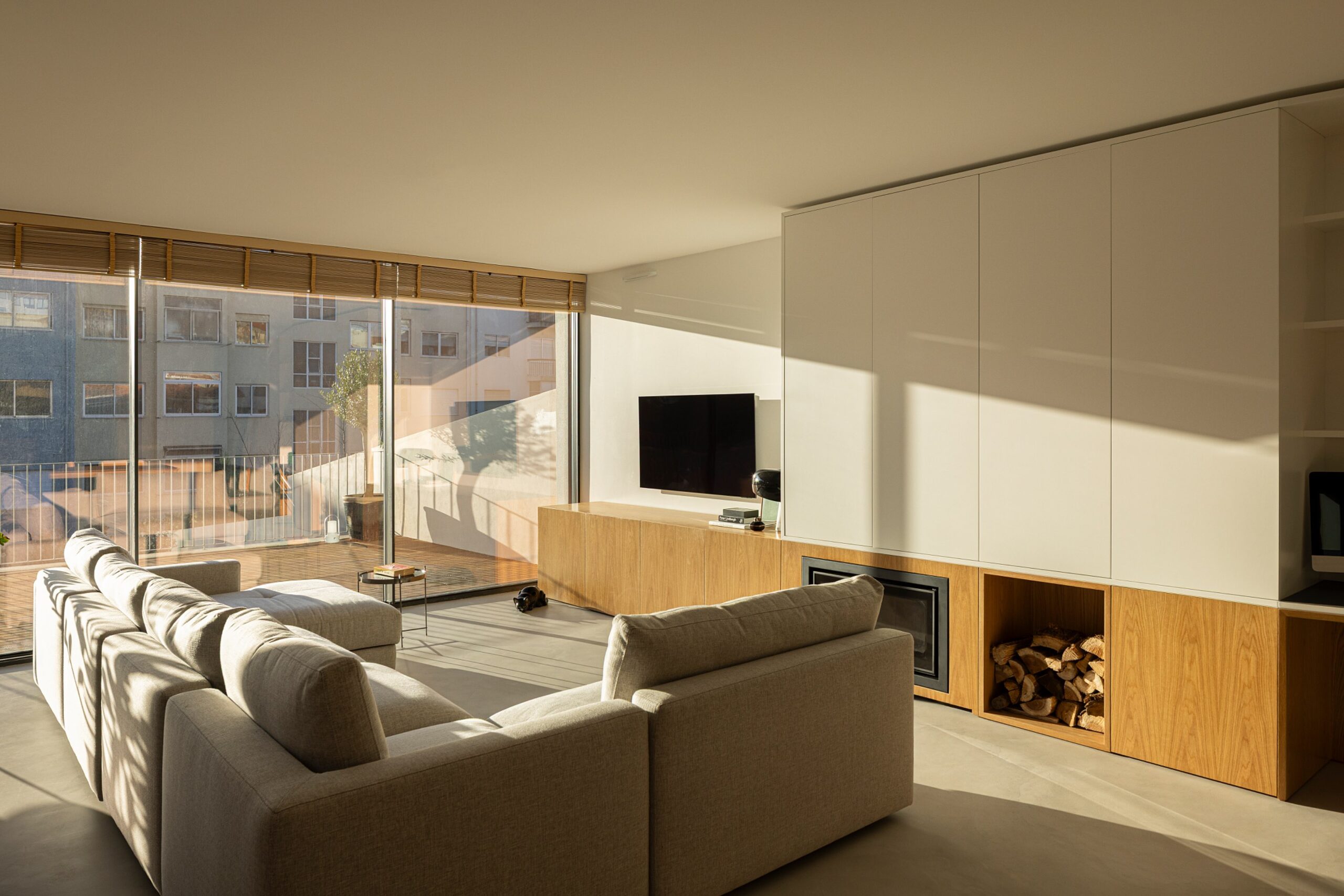 Sala de estar com vista para o exterior, sofá cinzento e móvel em madeira de carvalho — Casa sem Rua