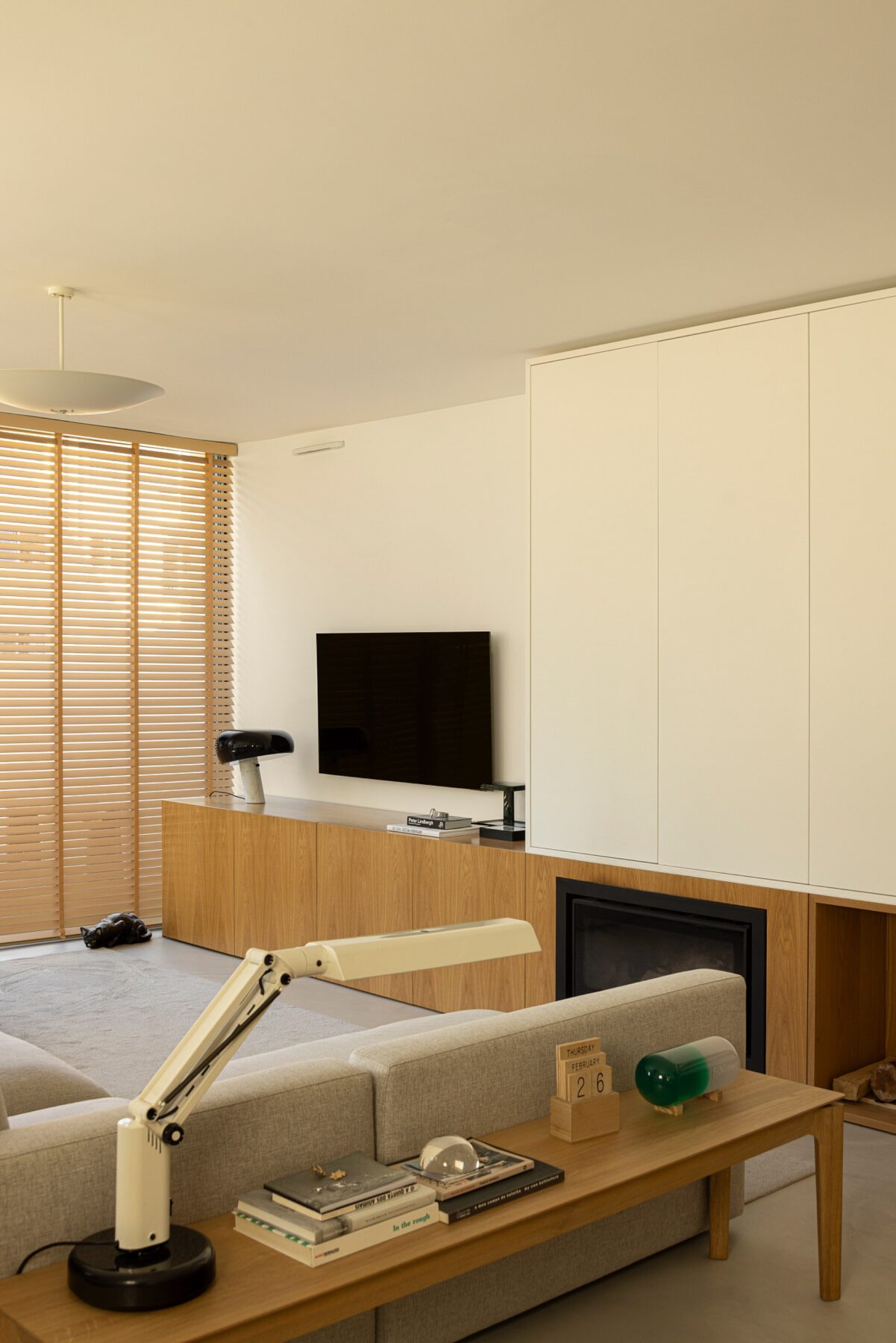 Sala de estar com candeeiro de mesa, sofá cinzento e móvel em madeira de carvalho — Casa sem Rua