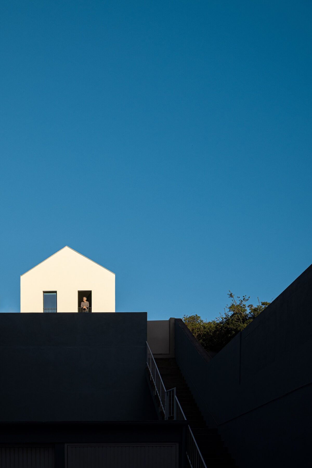 Fachada principal da moradia com revestimento branco, varanda e escadaria exterior — Casa sem Rua