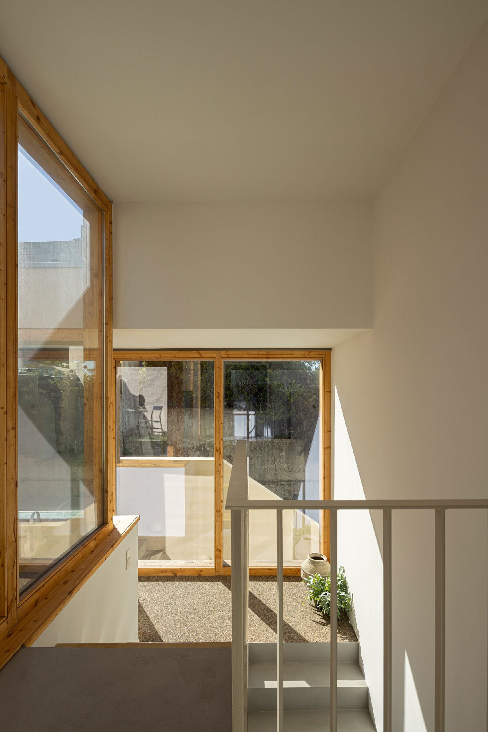 Escadaria interior com degraus em betão e madeira, e vão envidraçado — Casa sem Rua