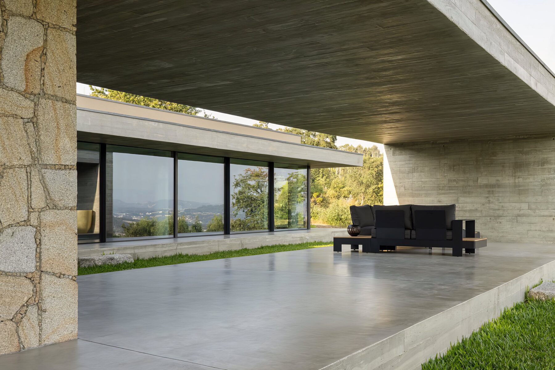 Alpendre exterior com pavimento em betão aparente, mobiliário de exterior e cobertura em betão moldado in situ — Quinta da Casa (Habitação QC)