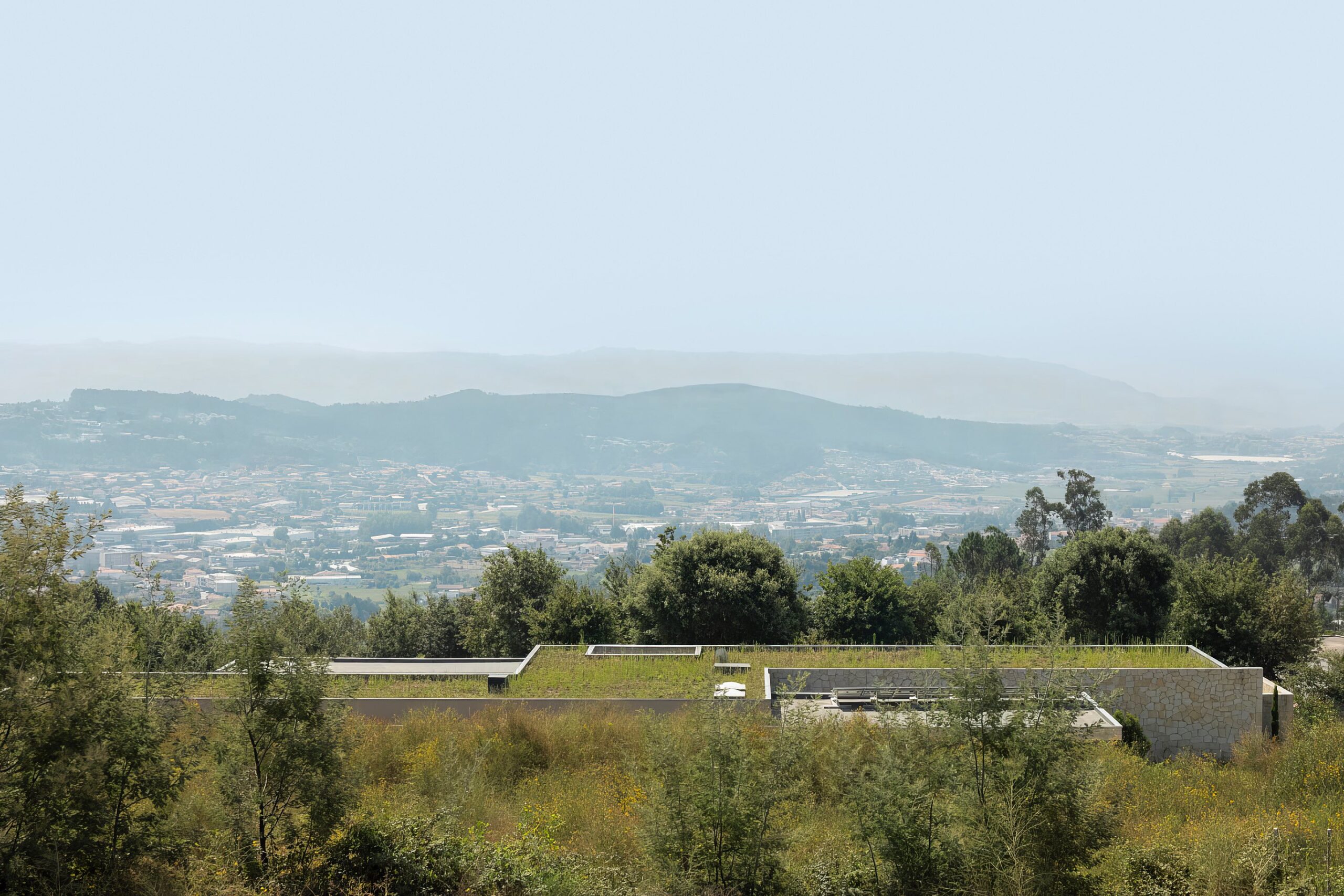 Moradia térrea com cobertura ajardinada, em betão aparente e alvenaria de granito, integrada na paisagem — Quinta da Casa (Habitação QC)