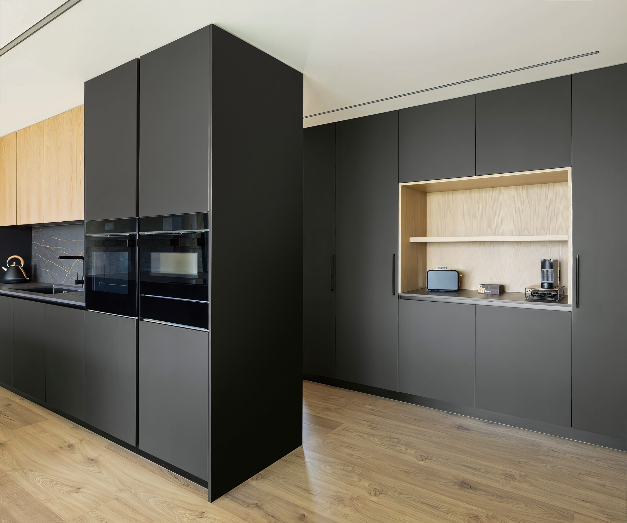 Cozinha com armários em madeira mel e cinzento escuro, pavimento em madeira e bancada em mármore negro — Quinta da Casa (Habitação QC)