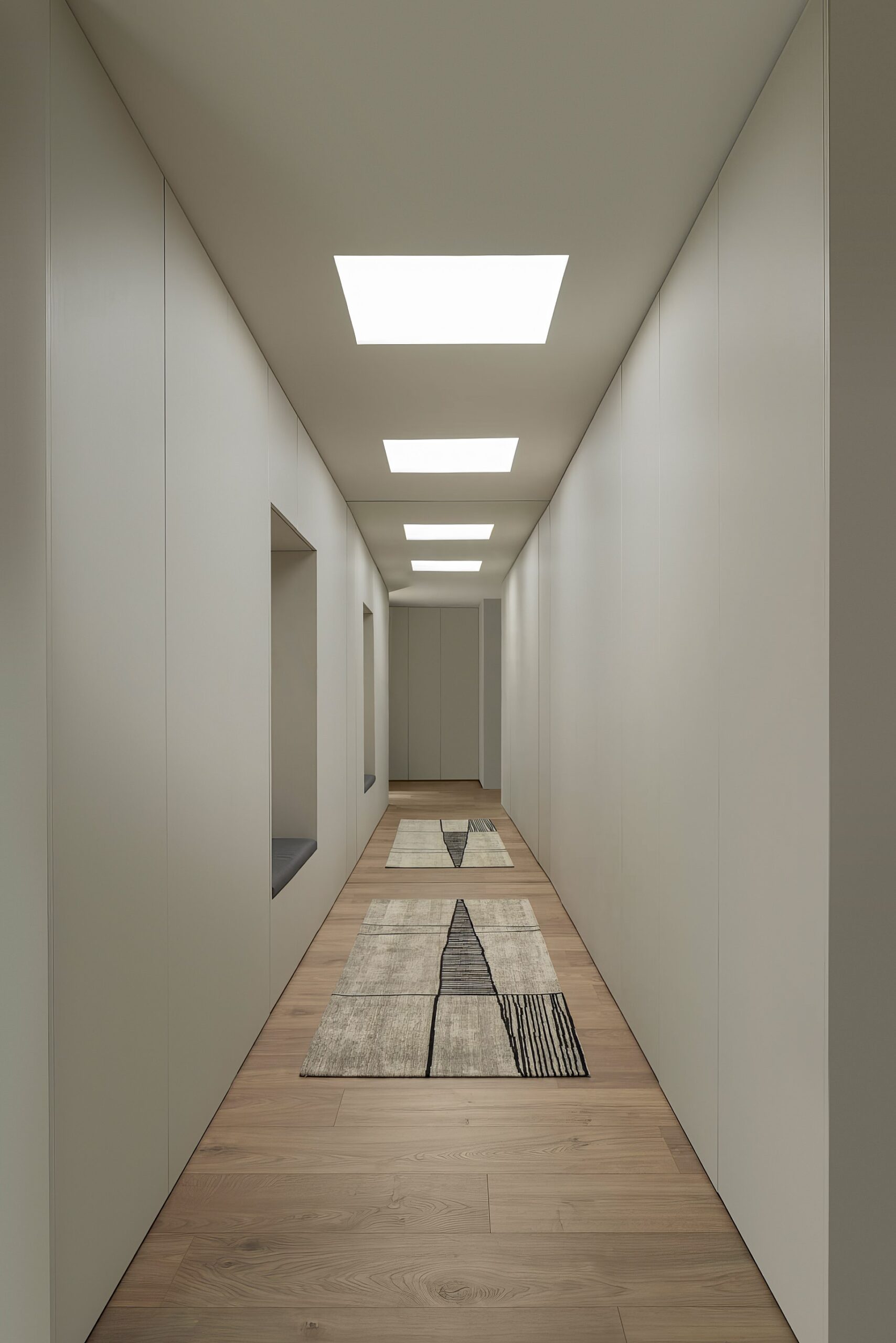 Corredor com pavimento em madeira, armários brancos e iluminação zenital, com tapetes geométricos — Quinta da Casa (Habitação QC)